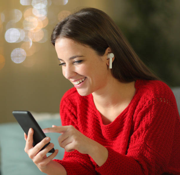 Junge Frau, die lächend auf ihr Smartphone schaut